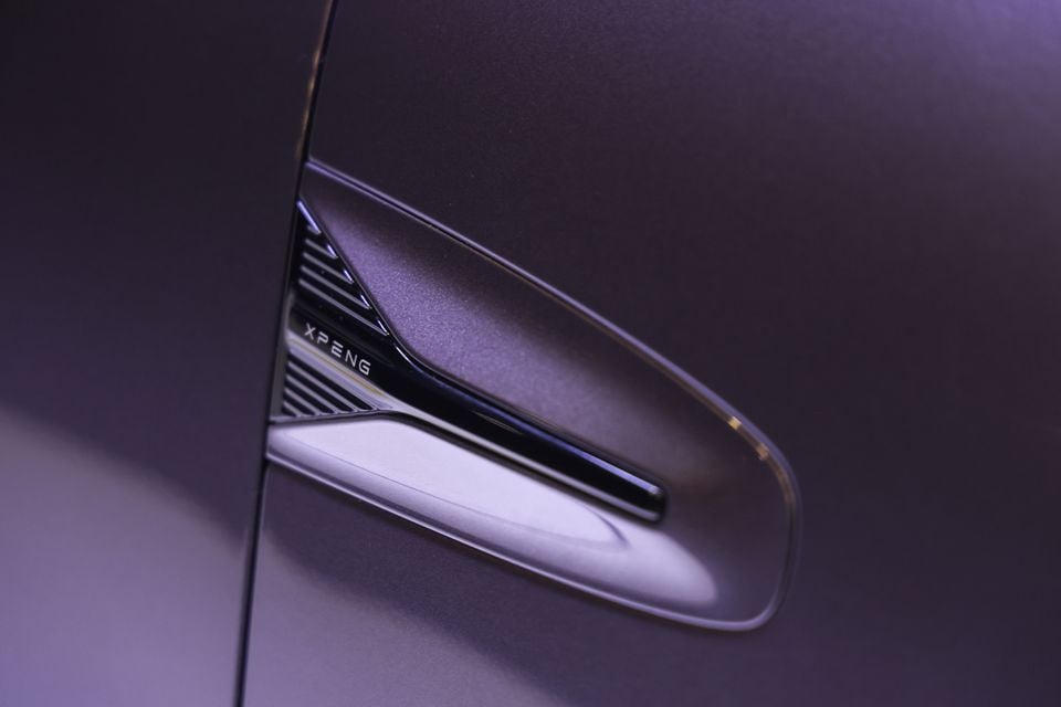 Close-up of a purple XPeng L03's door handle showing the XPeng logo and door body panel.