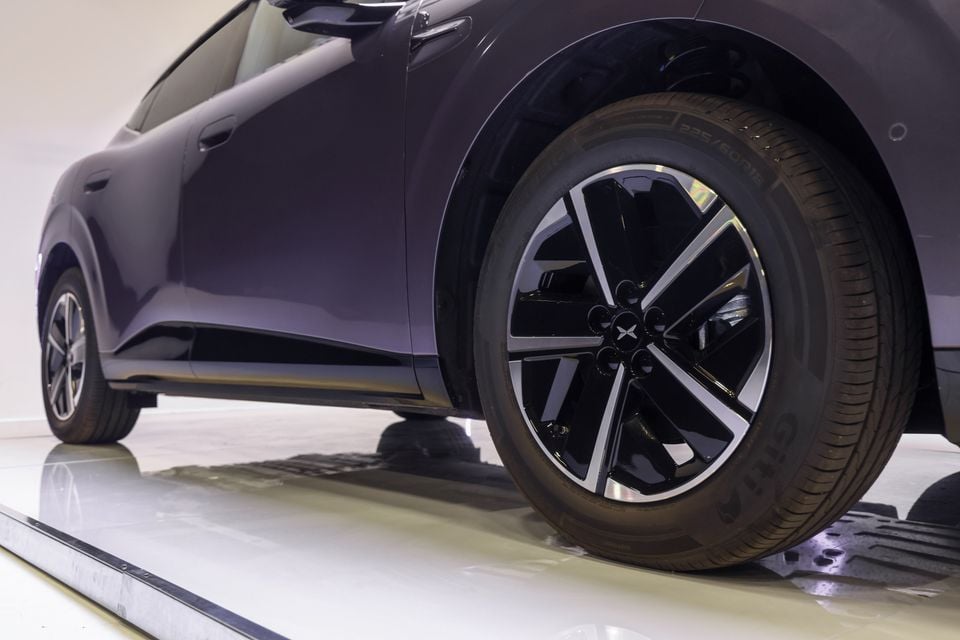 Close-up of the front wheel and alloy rim on a purple XPeng L03 SUV in a studio setting