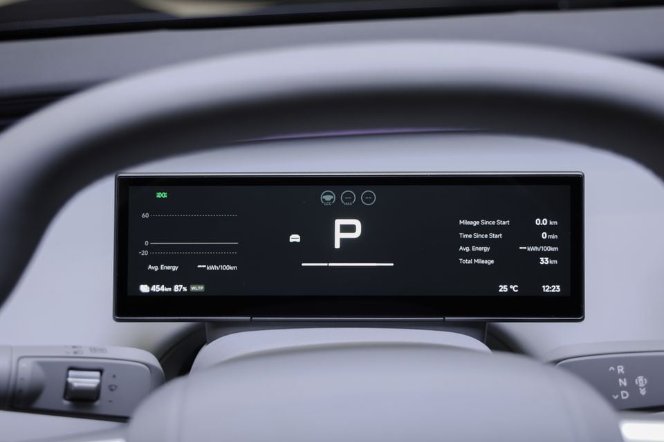 Digital instrument cluster of an electric vehicle showing the car in Park, battery range of 454km at 87 percent charge, and cabin temperature of 25 degrees