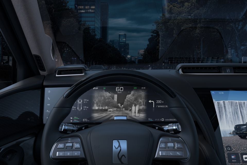 Driver's view of the Yangwang U8 cabin at night, showing the steering wheel, digital instrument cluster with night vision display and part of the central touchscreen