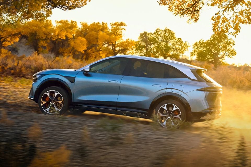 A blue Zeekr 7X SUV seen from the side while driving through an autumn landscape, kicking up dust