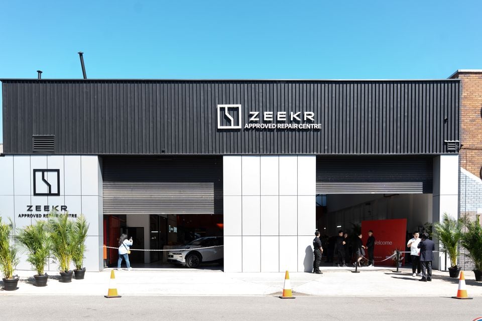 The exterior of a Zeekr Approved Repair Centre building in Sydney, with a white Zeekr vehicle visible inside and people gathered at the entrance.