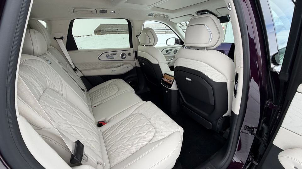 Rear seat interior of a Zeekr SUV showing light grey quilted leather bench seat and rear-seat entertainment screens on the front seat backs