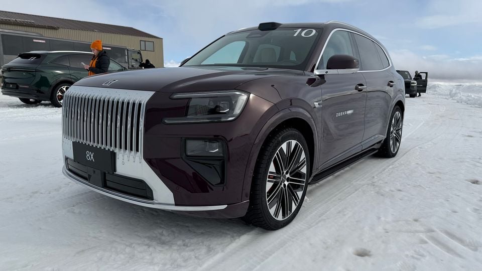 A dark burgundy Zeekr 8X SUV parked on snow, seen from the front-side angle, featuring a prominent vertical chrome grille