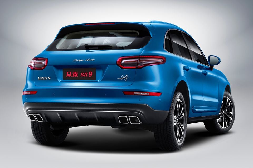A blue Zotye SR9 SUV seen from the rear three-quarter angle in a studio, showing its tail-lights and quad exhaust outlets
